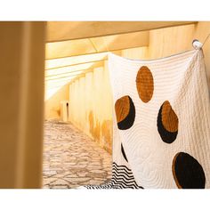 a quilt hanging on the side of a building next to a stone floor and wall