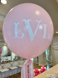 a pink balloon with the word ivv on it in front of chairs and tables