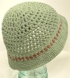 a green crocheted hat sitting on top of a glass bottle filled with water