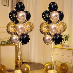 two tall black and gold balloons are next to each other