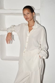 Oversized and relaxed fit. Shirt Collar Curved front and back hem. Back of the shirt fits longer than the front. Exposed Buttons. Mother pearl buttons. French seam finish Fits comfortably across shoulders, falls loose throughout the body. Oversized full-length sleeves with pleats and mother pearl button cuffs. Full-length sleeves with pleats and button cuffs Colour: Nata (Cream) One Size fits S/M/L Model is 1´82 - 5’10" Unisex 100% Pure Silk. Crepe de ChineMADE IN SPAIN French Seam, Shirt Fits, Mother Pearl, Pearl Buttons, Silk Crepe, Shirt Collar, Pure Silk, Length Sleeve, Full Length