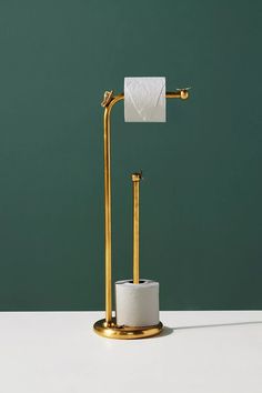 a gold toilet paper holder with a roll of tissue on it and a green wall in the background