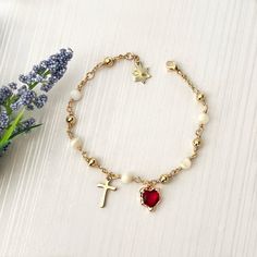 Our Sacred Heart rosary bracelet is handmade with Mother of Pearl gemstones, 18k gold-plated red cubic zirconia hearts, and 18k gold-plated beads. The Mother of Pearl gemstones symbolize purity and wisdom, while the red cubic zirconia heart represents the Sacred Heart of Jesus, radiating love and compassion. This rosary bracelet serves as a beautiful reminder of faith and grace. *  Adjustable from adult wrist 6 1/2" to 7 1/2". *  Total length: 8" (20cm). *  18k Gold-plated cubic zirconia heart. Gold-plated Rosary Bracelet For Gift, Adjustable Gold Crystal Bracelet For Valentine's Day, Elegant Beaded Bracelets With Charms For Valentine's Day, Elegant Gold Crystal Bracelet With Heart Charm, Dainty Handmade Gold Rosary Bracelet, Gold Crystal Bracelet For Valentine's Day Gift, Gold Cubic Zirconia Heart Bracelet For Valentine's Day, Valentine's Day Gold Crystal Bracelet With Heart Charm, Gold Crystal Bracelet With Charms For Jewelry Making