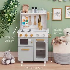 a toy kitchen set with a teddy bear and potted plant in the corner next to it