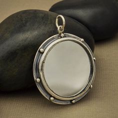 Mirror Pendant - Sterling Silver Mirror Frame, Framed Pendant, Art Deco Pendant, Reflection Charm, Art. Artist Pendant, Sterling Mirror. This sterling silver mirror pendant with granulation features a real mirror at the center of the design, and silver dots along the edge of the darkened, oxidized frame. The overall effect is moody, dramatic, and stormy. Spiritually, mirrors are closely associated with light, illumination, spiritual awareness and wisdom. Many believe mirrors reflect truth by ini Mirror Pendant, Art Nouveau Pendant, Art Deco Pendant, Monogram Jewelry, Mirror Frame, Silver Mirror, Celestial Jewelry, Spiritual Awareness, Vintage Mirror