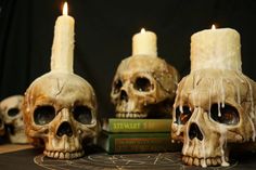 there are three candles that have been placed on top of some books and skull heads