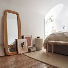 a bed room with a neatly made bed and a large mirror on the wall next to it