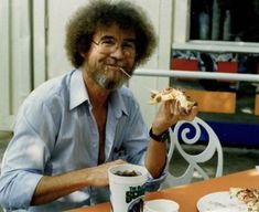 a man sitting at a table eating pizza