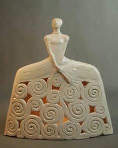 a white ceramic figurine sitting on top of a rock with swirly designs