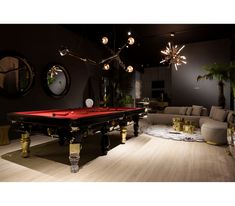 a pool table in the middle of a living room with couches and chandeliers