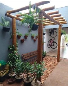 a wooden bench sitting under a pergoline covered with potted plants