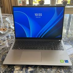 an open laptop computer sitting on top of a table next to a glass filled with water