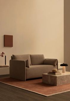 a living room with a couch, coffee table and lamp on the floor in front of a white wall