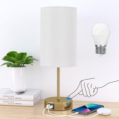 a lamp that is on top of a table next to a phone and a plant