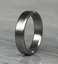 a wedding ring is shown on a wooden surface, with no one in the photo looking at it