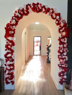 an archway decorated with red and white christmas decorations is shown in this hallway, while the light shines on the hardwood floor