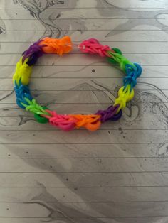 a rainbow colored bracelet on top of a piece of lined paper with pencils next to it