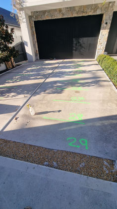 an empty driveway in front of a house with graffiti on the ground and two garage doors