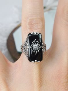 Black Glass/Stone & CZ Ring Grace Design#233 Custom Made I now offer this lovely Antique Art Deco/Edwardian design ring in sterling silver. This gorgeous ring is set with a stunning floral filigree embellished black glass/resin with a centered set 1mm white CZ. The Black glass is 18mm Long by 19mm Wide. The ring sits 19mm NS in the finger and 10mm EW on the finger. The inside of the band is marked 925 for sterling. Notice the beautiful leaf geometric design of the filigree band and setting. Art Deco Diamond Jewelry With Gemstone, Elegant Black Rings With Gemstone Accents, Fine Jewelry With Black Gemstone Accents, Classic Onyx Jewelry For Wedding, Elegant Onyx Jewelry With Diamond Accents, Elegant Onyx Diamond Ring Gift, Formal Cubic Zirconia Jewelry With Filigree Details, Art Deco Diamond White Jewelry With Gemstone, Formal Cubic Zirconia Jewelry With Filigree