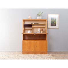 a wooden cabinet with shelves and vases on top in a room that has carpeted flooring