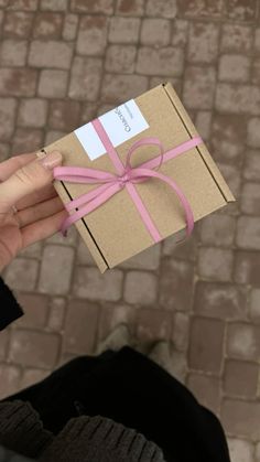 a person holding a brown box with pink ribbon