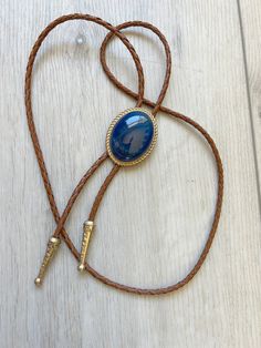 This awesome bolo tie has a southwestern design and blue agate centerpiece. Each of our stones is unique . The cord is genuine brown leather. It has a gold metal frame and matching gold tips. Our bolos pair nicely with many of our belt buckles! They make wonderful gifts. The western bolo tie rope length is 100cm(39") ; charm agate stone pendant size is 5*4cm(1.97*1.57in) Adjustable Gold Western Bolo Ties, Adjustable Gold Concho Jewelry, Gold Western Bolo Tie, Western Style Brown Jewelry With Adjustable Length, Brown Western Jewelry With Adjustable Cord, Brown Western Jewelry With Adjustable Length, Adjustable Vintage Hand Tooled Bolo Tie, Vintage Adjustable Hand Tooled Bolo Tie, Vintage Gold Jewelry For Rodeo