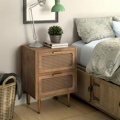 a bedroom with a bed, nightstand and lamp on the side table in front of it