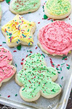 decorated cookies on a baking sheet with sprinkles and frosting in the shape of christmas trees