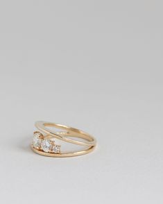 a gold ring with two diamonds on top and one diamond in the middle, against a white background