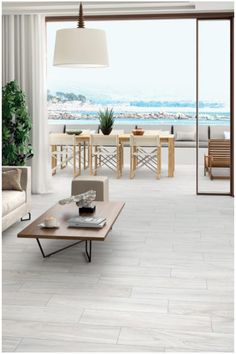 a living room filled with furniture next to a large glass door that leads out to the beach