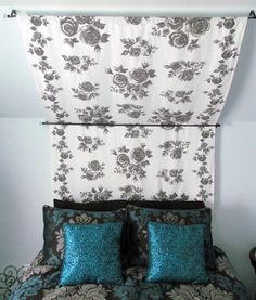 a bed with two pillows on top of it next to a wall hanging from the ceiling