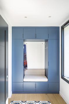 an empty room with blue cabinets and a white bench in the corner, next to a window