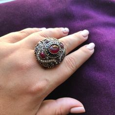 a woman's hand with a ring on top of her finger and purple fabric