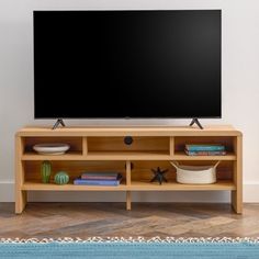 a flat screen tv sitting on top of a wooden entertainment center next to a blue rug