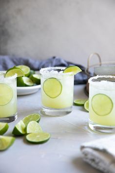 three margaritas with lime slices and sugar on the rim, sitting on a table