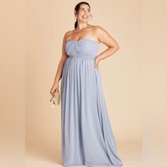 a woman in a strapless blue dress poses for the camera with her hands on her hips