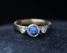 a gold ring with a blue sapphire and three diamonds