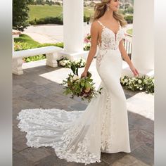 a woman in a white wedding dress standing on a patio with flowers and greenery