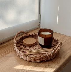 a wicker basket with a candle and some sticks in it on a wooden table