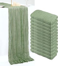 a stack of green towels sitting next to each other on top of a white table