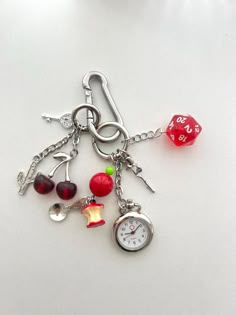 a keychain with various items attached to it on a white surface, including a clock and dice