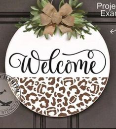 a leopard print welcome sign hanging on a door with the words welcome in black and white