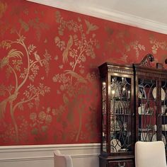 a dining room with red wallpaper and white chairs in front of a china cabinet