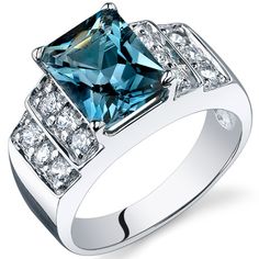 a white gold ring with a blue sapphire and diamonds on the sides, set against a white background