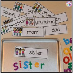 a metal tray filled with pictures and words on top of a wooden table covered in magnets