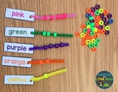 colorful beads and name tags are displayed on a wooden surface with the words pink, green, purple, orange, and yellow