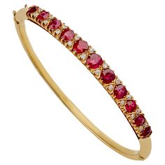 Dating from the end of the 19th century, this ruby and diamond bangle is set in 18K gold. The hinged form is set across the top with eleven graduating oval cushion-shape faceted rubies, approximate total weight 4.00 carats, alternating with pairs of old mine-cut diamonds, completed by a plain polished gold bangle. A classic jewel of modern form with pristine old gems, this bangle can stack with other bejeweled bracelets or stand alone as a vivid band of color and sparkle. Product Details: Item #: BA-20924 Circa: 1895 Materials: 11 round rubies (approximate total weight 4.00 carats); 20 old European-cut diamonds (approximate total weight 0.30 carat); 18K Gold Macklowe Gallery Curator's Notes: In the 1890s women of fashion wore jeweled bangles several to a wrist. The 1894 Sir Fildes portrait 1890s Women, Ruby Bangles, Ruby Bracelet, Diamond Bangles Bracelet, Gold Bangle, Diamond Bangle, European Cut Diamonds, Diamond Bracelets, Gold Bangles