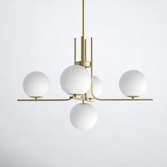 a modern chandelier with five white balls hanging from it's brass frame