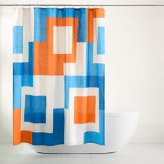 an orange and blue shower curtain is hanging in a white bathtub next to a toilet