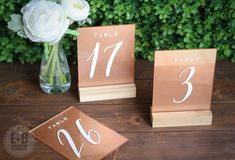 the table numbers have been placed on wooden blocks with flowers in a vase next to them